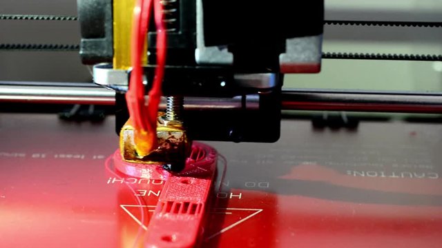 3d printer manufacturing a red part in abs