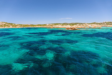 Fototapeta premium Panoramic view of the pink granite rock formations and the clear and transparent waters in the Maddalena archipelago in Sardinia, Italy.