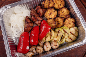 Grilled potatoes with grilled vegetables and meat on a baking tray