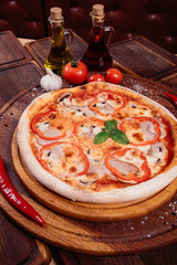 Appetizing pizza with peppers, mushrooms and ham on wooden background