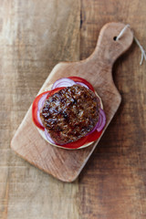 Tasty humburger with tomatoes and red onion. Rustic stone background. Top view.