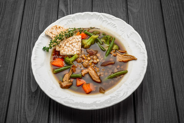Lentil soup with porcini mushrooms on a dark background