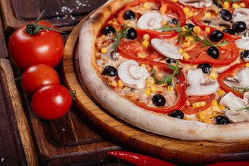 Pizza with sliced vegetables on rustic wood, vintage style