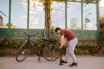 Handsome young caucasian man pumps a bicycle tire
