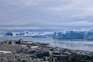 Antarctic base e before glacier front with stone beach landscape in Antarctica, blue sky, Stonington Island
