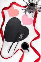 Valentine's Day love romantic dinner setup on white background, red ribbon, black heart shaped plate and  flowers