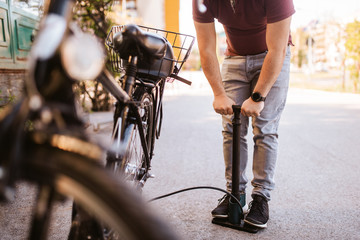 Fototapeta na wymiar Handsome young caucasian man pumps a bicycle tire