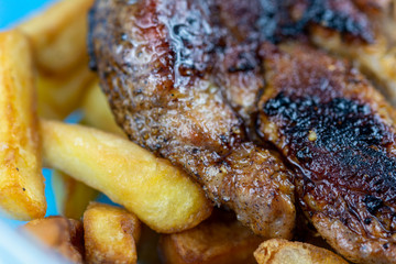 Juicy, delicious beef steak cooked in a frying pan with french fries
