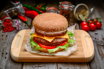 big cheeseburger with melted cheese and on wooden background
