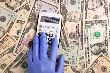 Hand in glove debts on calculator against background of dollars