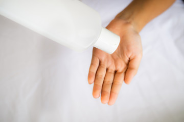 Hand applying sanitizer from the bottle on a white background.