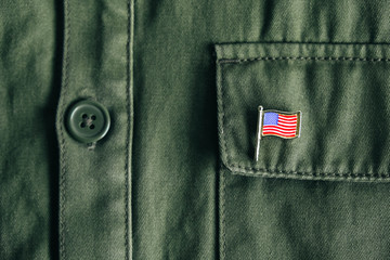 USA flag pin badge on green jacket pocket. Top view. Copy, empty space for text
