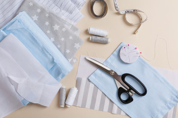Process of sewing of bed linen from grey, white & blue cotton. Sewing kit. Fabric, threads, measuring tape  on beige background. DIY zero waste recycling. Do it yourself. Homemade sewing. Home craft. 