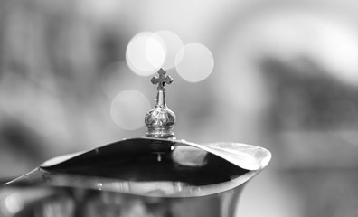 A metal jug with a cross on top and cups of water are used for drinking after the sacrament of...
