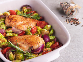 baked chicken fillet with vegetables, brussels sprouts, onions tomato close up