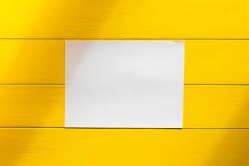 Rough shadow. Retro style wooden background on wooden background. A sheet of white paper in the center. Horizontal disposition.