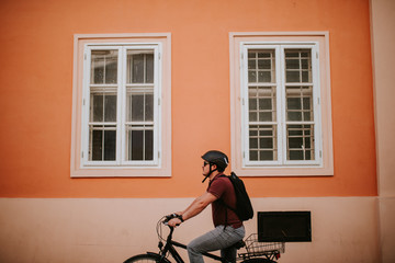 Fototapeta premium Handsome young caucasian man riding a bicycle by the house