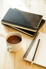 cup of hot chocolate on wooden background with notebook.  Work from home concept.