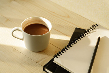 cup of hot chocolate on wooden background with notebook.  Work from home concept.