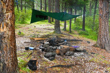 camping in woods, place for eating, green awning over hearth fire