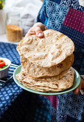 Plain chapati or tortillas flatbread. Naan bread. Vegan food. Woman hands