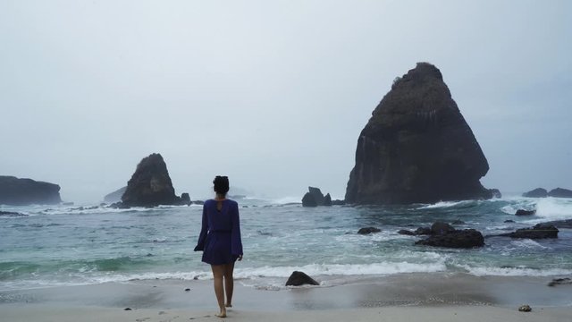 Rear view of young woman walks on Papuma beach