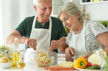 Portrait of senior couple cooking together at kitchen