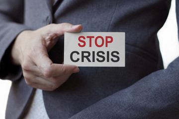 Business woman holding a card with the inscription STOP CRISIS