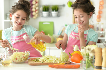 Cute girls preparing delicious fresh salad in kitchen