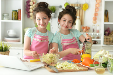 Cute girls preparing delicious fresh salad in kitchen