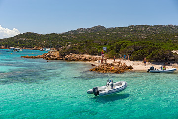 Various tourist boats are stationed in the clear and transparent waters in the Maddalena archipelago in Sardinia, Italy.