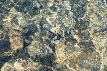 rocks and pebbles at bottom of riverbed through clear water