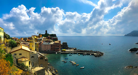 Naklejka premium Gorgeous panoramic view of the bay in Vernazza. Landscape of Santa Margherita di Antiochia Church, the medieval Doria Castle and marina on a beautiful sunny day. Cinque Terre, Ligurian coast, Italy.