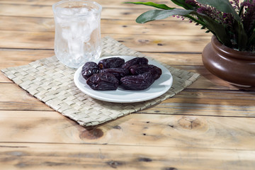 Dates and ice water on the wooden table and selective focus