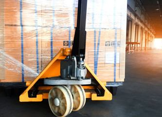 close up hand pallet truck with large shipment pallet goods ,interior of warehouse dock load cargo