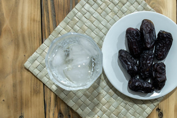 Dates and ice water on the wooden table and selective focus