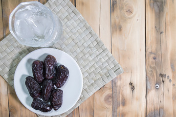 Dates and ice water on the wooden table and selective focus