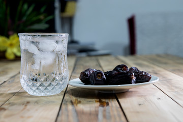 Dates and ice water on the wooden table and selective focus