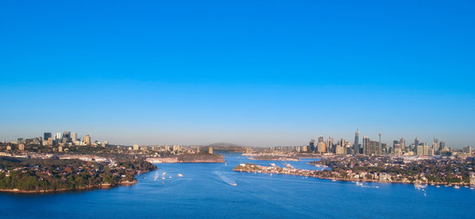 Panoramic drone aerial view over Sydney harbour on a cloudy sunset showing the nice colours of the harbour foreshore