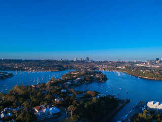 Naklejka premium Panoramic drone aerial view over Sydney harbour on a cloudy sunset showing the nice colours of the harbour foreshore