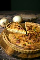 Homemade cheesy quiche lorraine for brunch. set on wooden cafe table background.