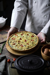 Homemade cheesy spinach quiche for brunch. set on wooden cafe table background.