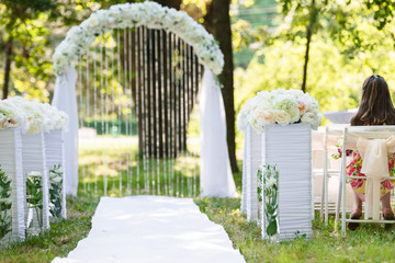 Fototapeta premium White luxury wedding ceremony decorations outdoor in the summer park. Table, chairs and weddinh decorated arch