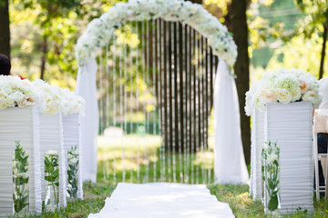 White luxury wedding ceremony decorations outdoor in the summer park. Table, chairs and weddinh...