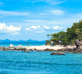 Obraz premium a deserted sunny beach with white sand and large stones, surrounded by the blue sea.