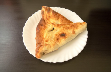 Famous traditional Arabic, Middle East, Israel cuisine. Spinach Manakish on dark wooden background. Spinach triangle pie on white plate