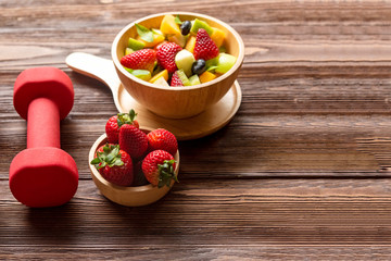 Healthy Fruits. Fresh fruits salad diet slim fit with dumbbells sport equipment for healthy lifestyle women. Weight Loss and Diet Concept