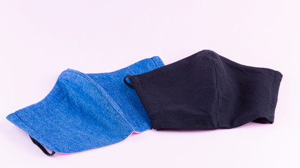 Protective masks on a pastel background. Antivirus mask made of cotton. Blue and black face mask during a virus COVID-19. Handmade face masks on pink background