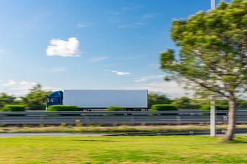 Fototapeta na wymiar Truck with refrigerated semi-trailer driving on the highway with a blue sky with some clouds