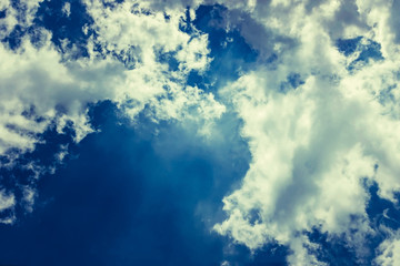 Fototapeta premium Fluffy white solar clouds in the twilight light float against the dark blue sky. Divine view. Concept and background dream, success, luck, Halloween. copy space